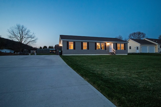 back of house at dusk with driveway and a lawn