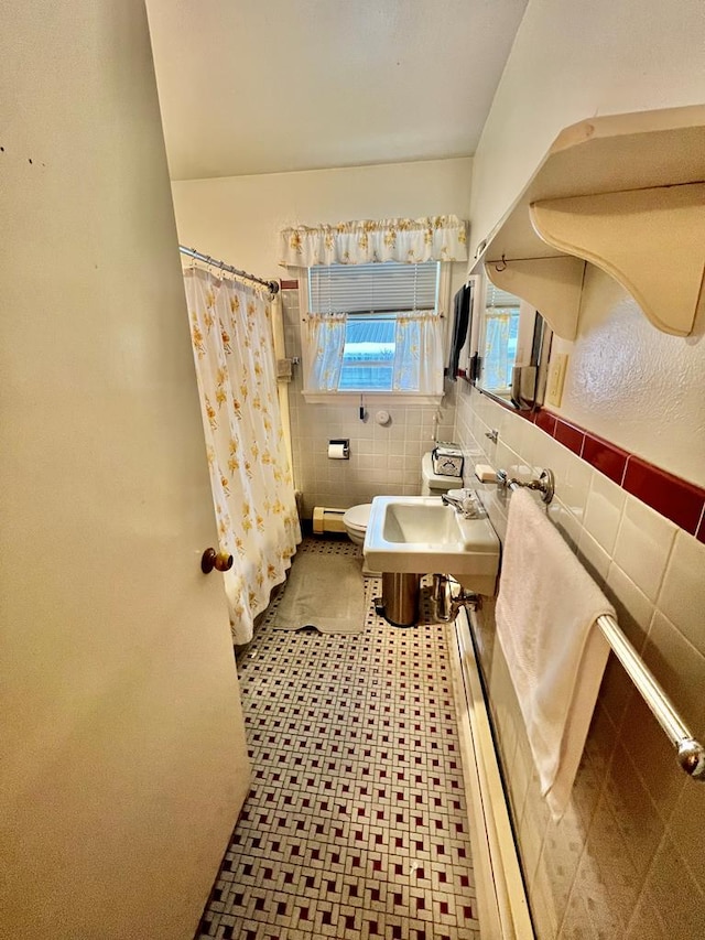 bathroom featuring a shower with curtain, toilet, sink, and tile walls