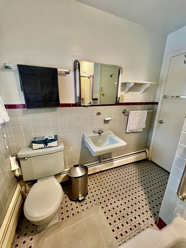 bathroom featuring sink, baseboard heating, tile patterned flooring, tile walls, and toilet