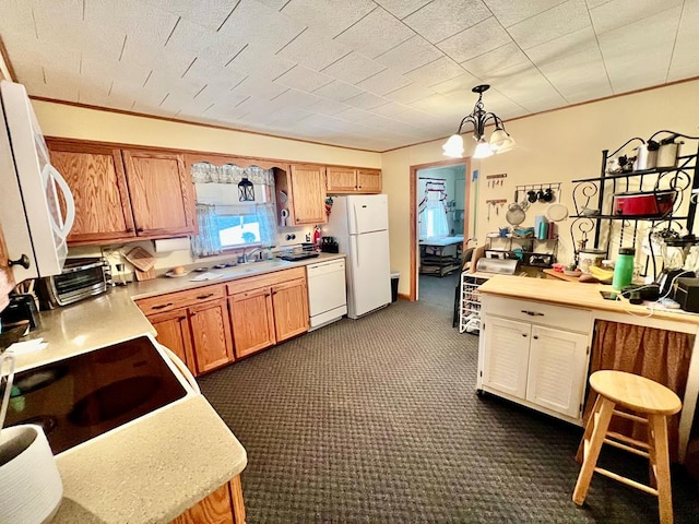 kitchen with white appliances, an inviting chandelier, dark colored carpet, ornamental molding, and decorative light fixtures