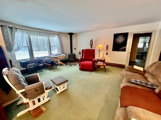 living room featuring a baseboard heating unit, carpet, and a wood stove