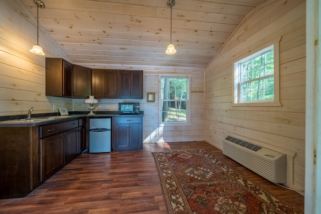 kitchen with pendant lighting, dark hardwood / wood-style flooring, lofted ceiling, and wooden walls