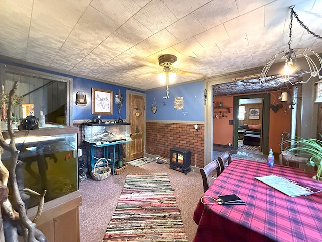 dining area featuring carpet floors, wainscoting, and a wood stove