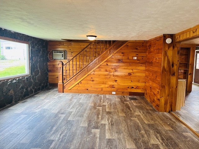 96 E St, Towanda, PA 18848 - unfurnished living room featuring a textured ceiling, wood finished floors, stairway, a wall mounted air conditioner, and wood walls