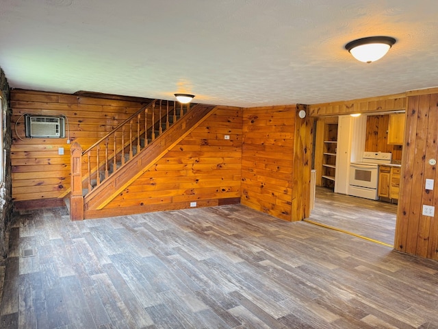 96 E St, Towanda, PA 18848 - unfurnished living room with wood finished floors, wood walls, stairway, an AC wall unit, and a textured ceiling