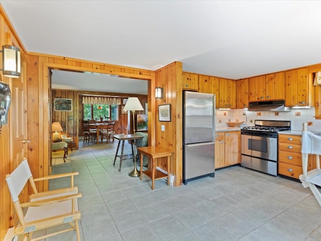 kitchen featuring stainless steel appliances, tasteful backsplash, and wooden walls