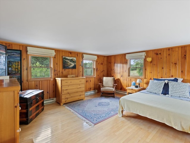 bedroom featuring light wood-type flooring, multiple windows, and a baseboard heating unit