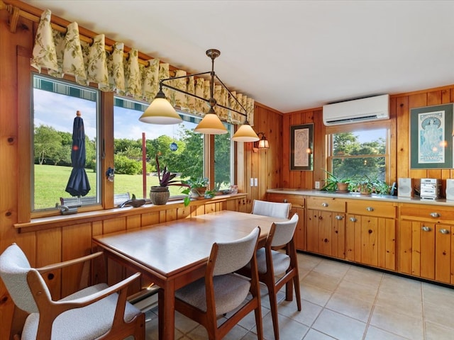 kitchen featuring a wall unit AC, wooden walls, light tile patterned floors, and decorative light fixtures