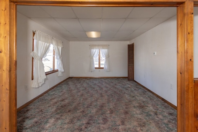 carpeted empty room featuring a drop ceiling