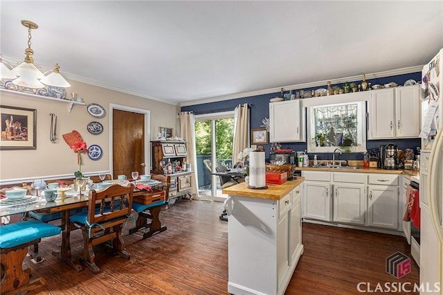 kitchen with decorative light fixtures, white cabinetry, dark hardwood / wood-style floors, butcher block counters, and sink