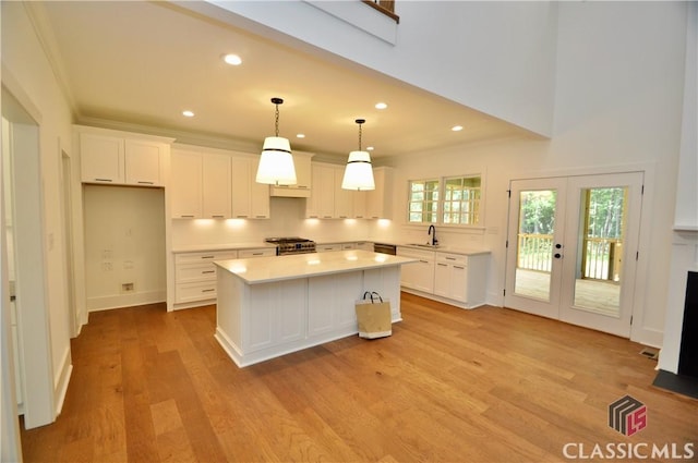 kitchen with french doors, sink, crown molding, a center island, and white cabinets