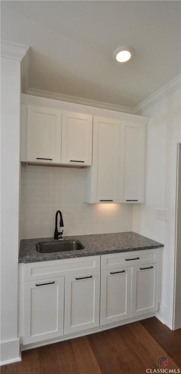 kitchen featuring white cabinetry, sink, dark hardwood / wood-style flooring, decorative backsplash, and ornamental molding