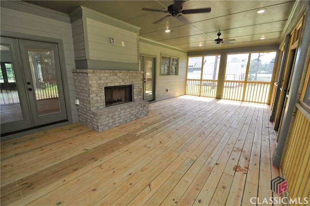 wooden terrace with french doors, ceiling fan, and a fireplace