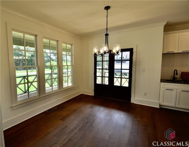 unfurnished dining area featuring crown molding, an inviting chandelier, dark wood-type flooring, and sink