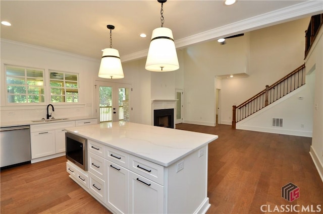 kitchen featuring dishwasher, white cabinetry, hanging light fixtures, a kitchen island, and built in microwave