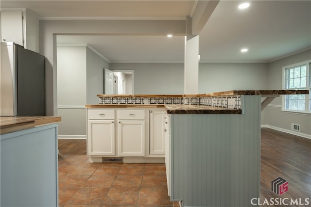 kitchen featuring ornamental molding, stainless steel refrigerator, white cabinetry, and tile flooring