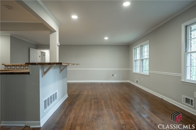 interior space featuring dark hardwood / wood-style flooring, ornamental molding, and a wealth of natural light