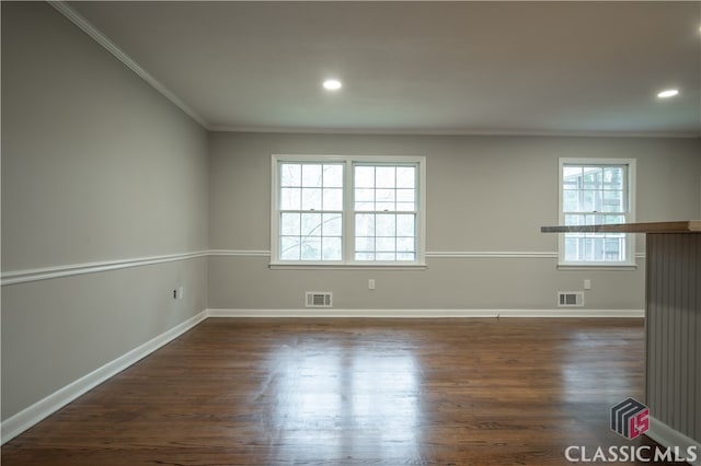 spare room featuring plenty of natural light, crown molding, and dark wood-type flooring