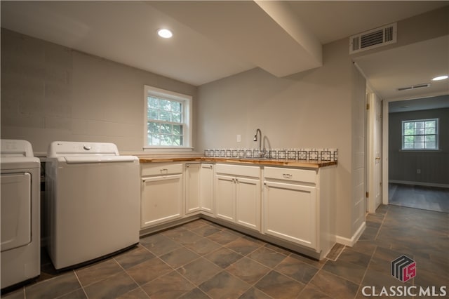 laundry room with dark tile floors, sink, cabinets, and washer and clothes dryer