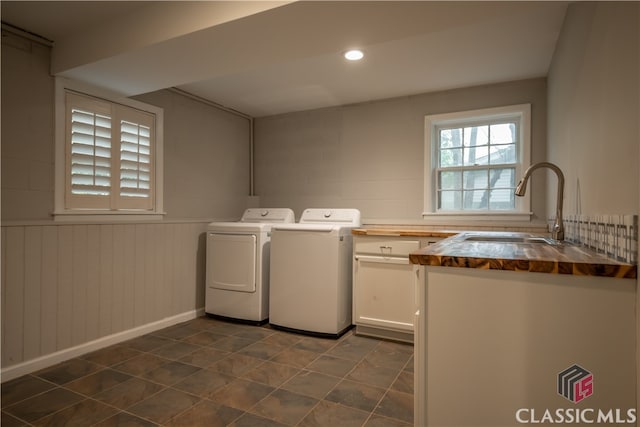 washroom with washing machine and clothes dryer, dark tile flooring, and sink