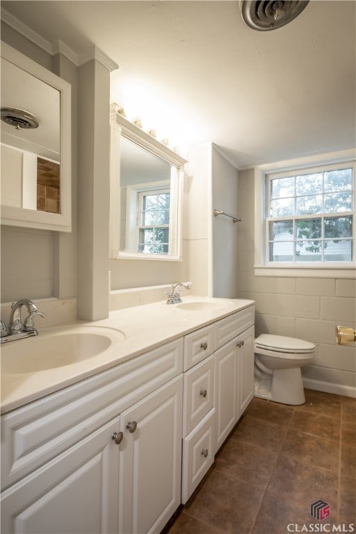 bathroom featuring toilet, double vanity, tile floors, and a wealth of natural light