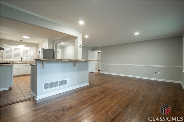 kitchen featuring stainless steel fridge, a breakfast bar area, light hardwood / wood-style floors, sink, and white cabinets