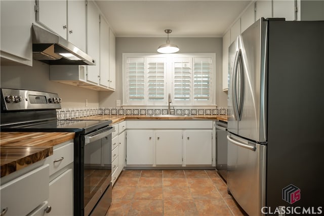 kitchen featuring pendant lighting, sink, stainless steel appliances, light tile flooring, and white cabinetry