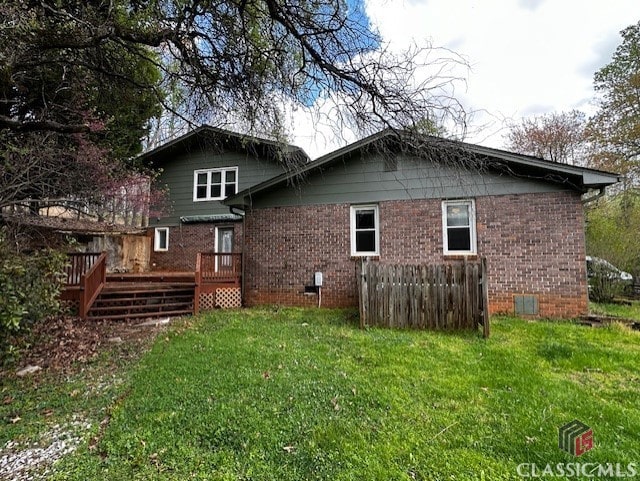 rear view of property with a yard and a wooden deck