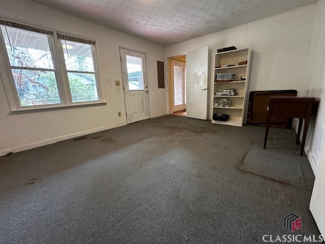 interior space with a textured ceiling and dark colored carpet