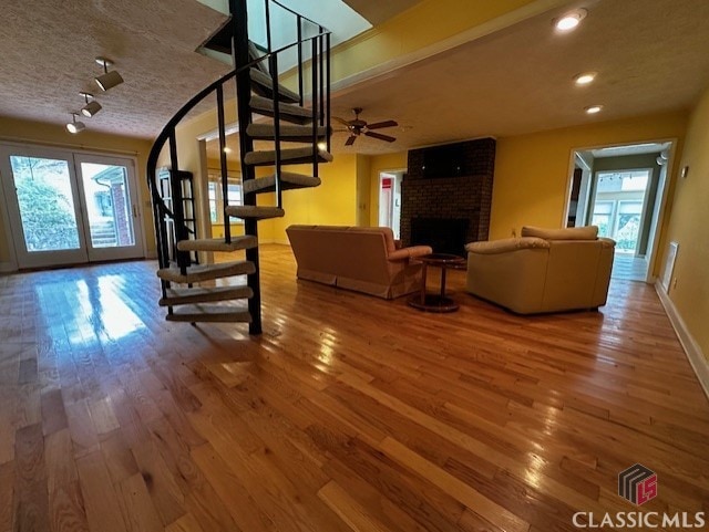 living room with a fireplace, ceiling fan, wood-type flooring, and plenty of natural light