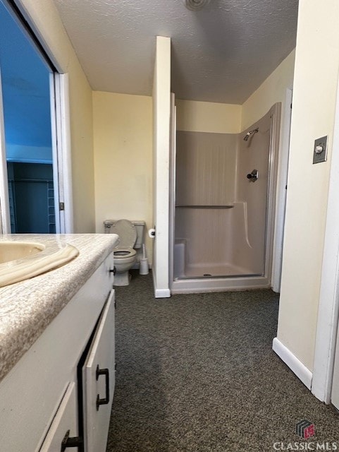 bathroom with toilet, a shower, vanity, and a textured ceiling