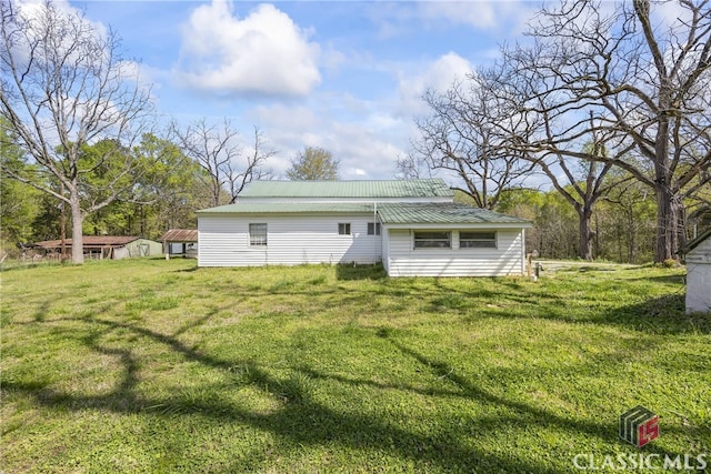 back of property featuring a storage shed and a yard