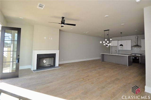 unfurnished living room featuring ceiling fan, sink, and light hardwood / wood-style flooring