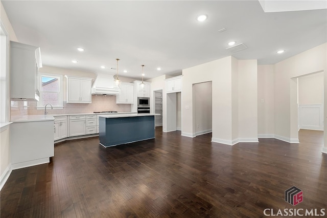 kitchen with premium range hood, a kitchen island, appliances with stainless steel finishes, and dark hardwood / wood-style flooring