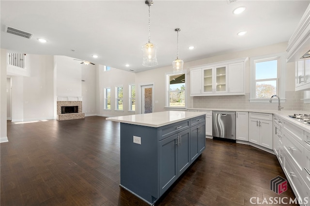 kitchen featuring appliances with stainless steel finishes, a fireplace, white cabinetry, dark hardwood / wood-style flooring, and pendant lighting