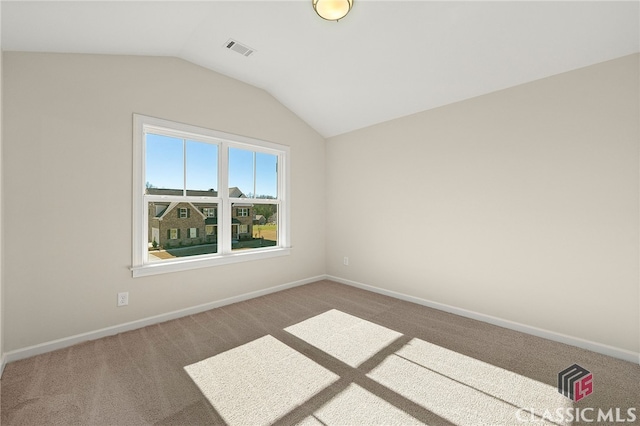 spare room featuring carpet and vaulted ceiling