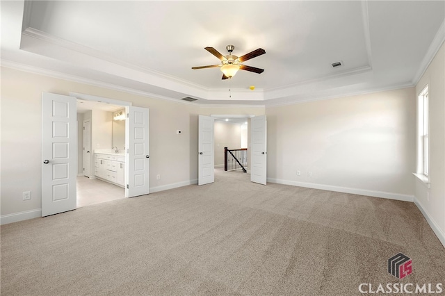 spare room with a raised ceiling, ceiling fan, light carpet, and ornamental molding