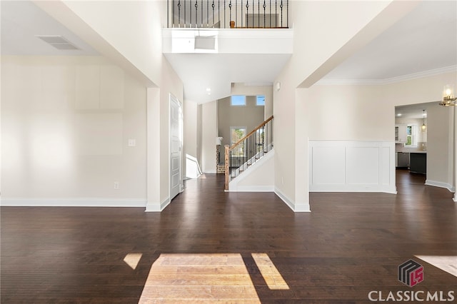 foyer entrance featuring dark hardwood / wood-style flooring, a towering ceiling, and ornamental molding