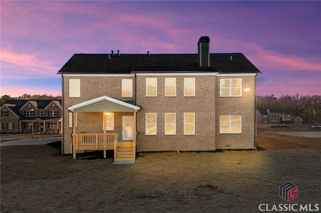 back house at dusk featuring a deck