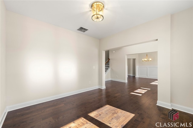 spare room featuring hardwood / wood-style flooring and a chandelier