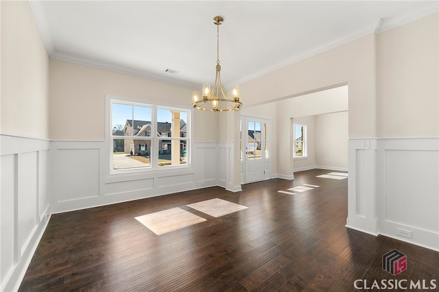 empty room featuring dark hardwood / wood-style flooring, an inviting chandelier, and ornamental molding