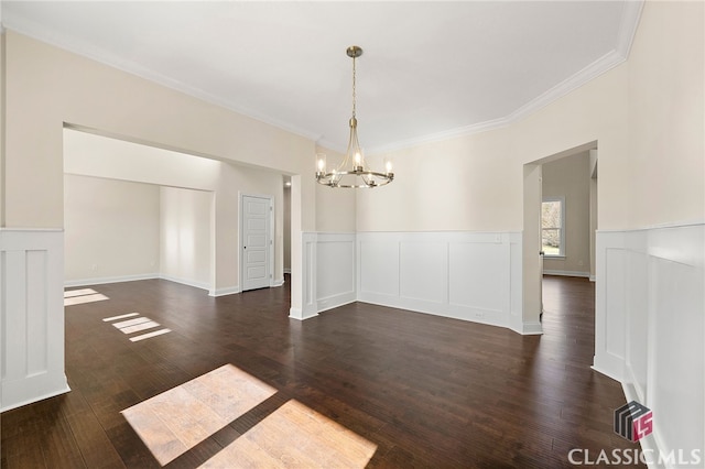 unfurnished room featuring dark hardwood / wood-style flooring, crown molding, and an inviting chandelier