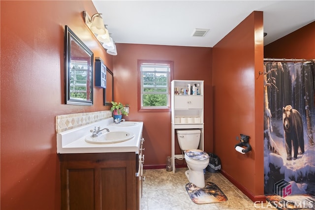 bathroom featuring tile floors, dual bowl vanity, and toilet