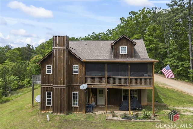 back of property with a sunroom and a lawn