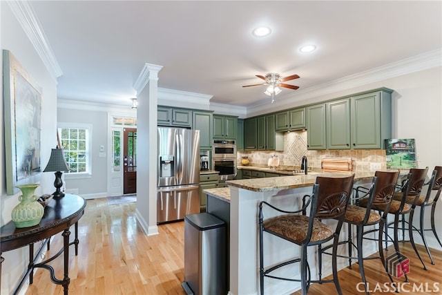 kitchen featuring light stone countertops, stainless steel appliances, green cabinets, kitchen peninsula, and crown molding