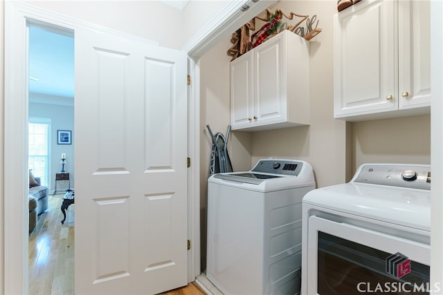 laundry area with washing machine and dryer, light hardwood / wood-style flooring, and cabinets