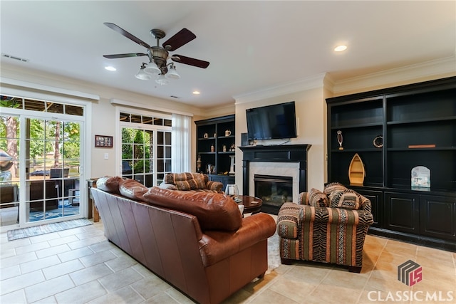 tiled living room with built in shelves, ceiling fan, and ornamental molding