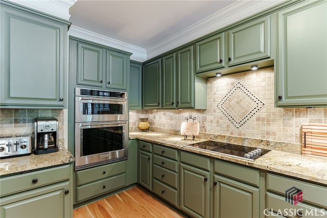 kitchen featuring light stone countertops, ornamental molding, stainless steel double oven, black electric cooktop, and green cabinets