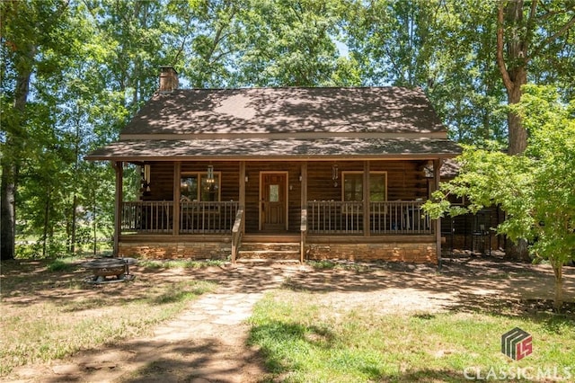 cabin with covered porch and an outdoor fire pit