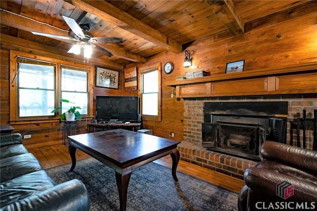 living room featuring hardwood / wood-style floors, wooden walls, ceiling fan, beam ceiling, and wood ceiling